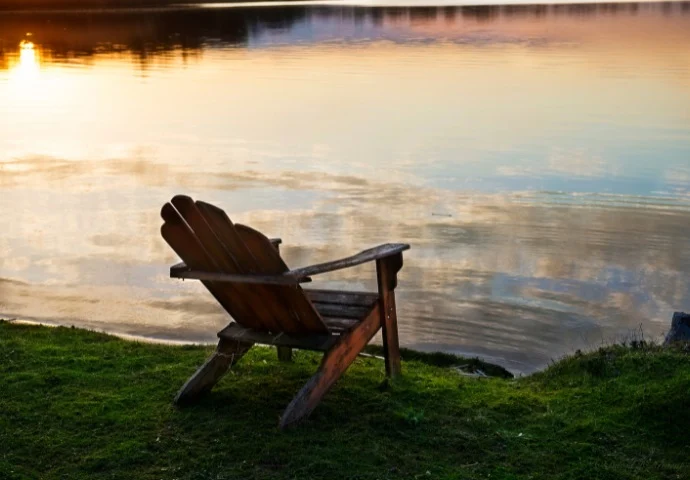 Adirondack chair sitting next to lake